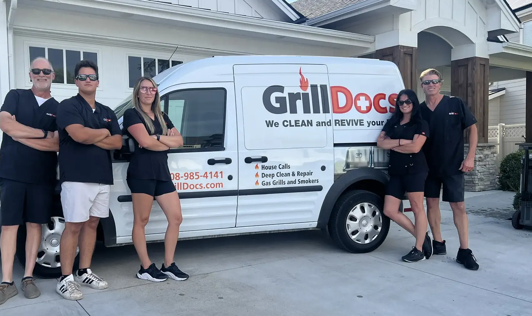 Five members of the Grill Docs team in black work scrubs, standing beside a white Grill Docs van.